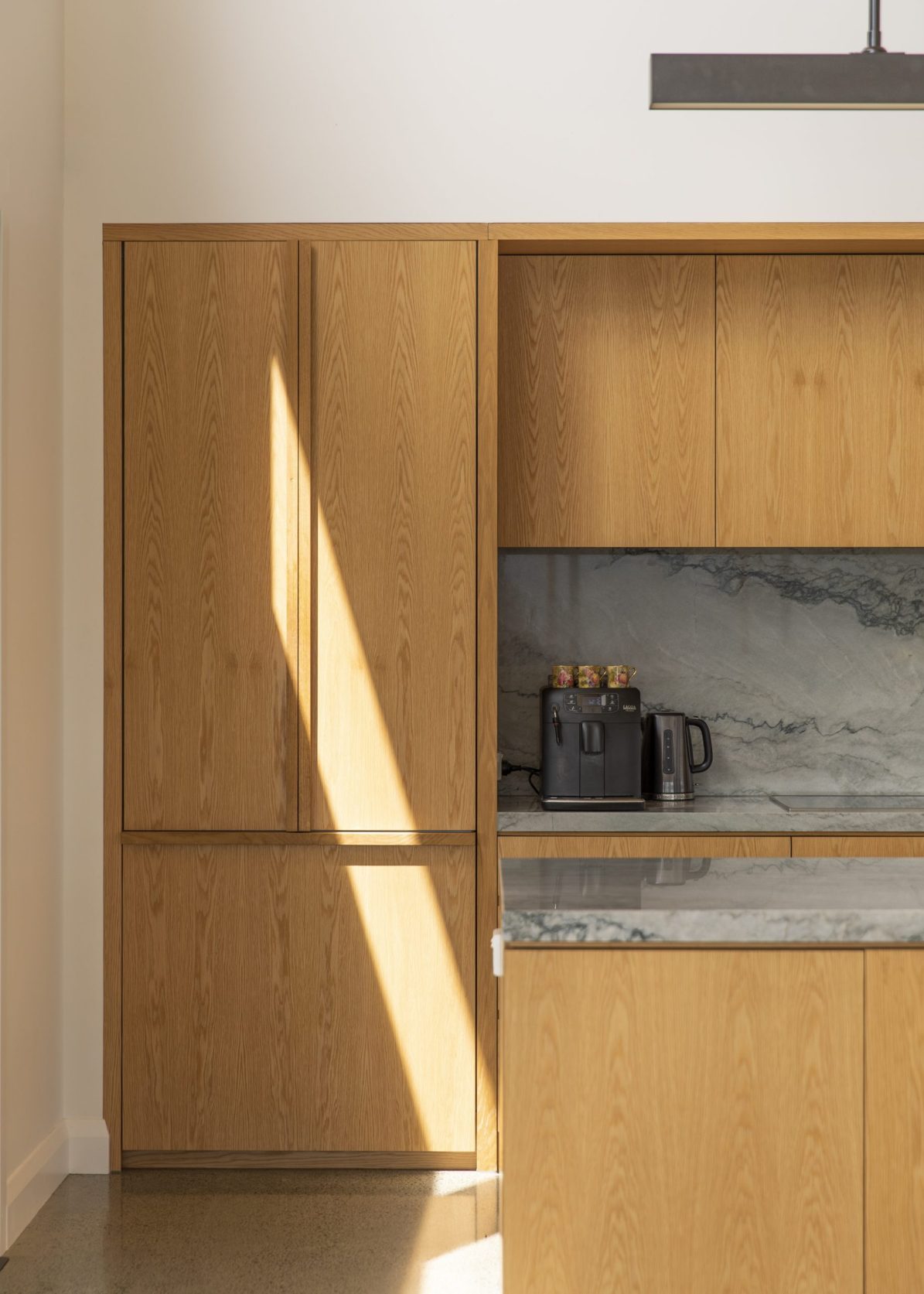 Close-up of integrated fridge with custom American oak cabinetry and bespoke handles