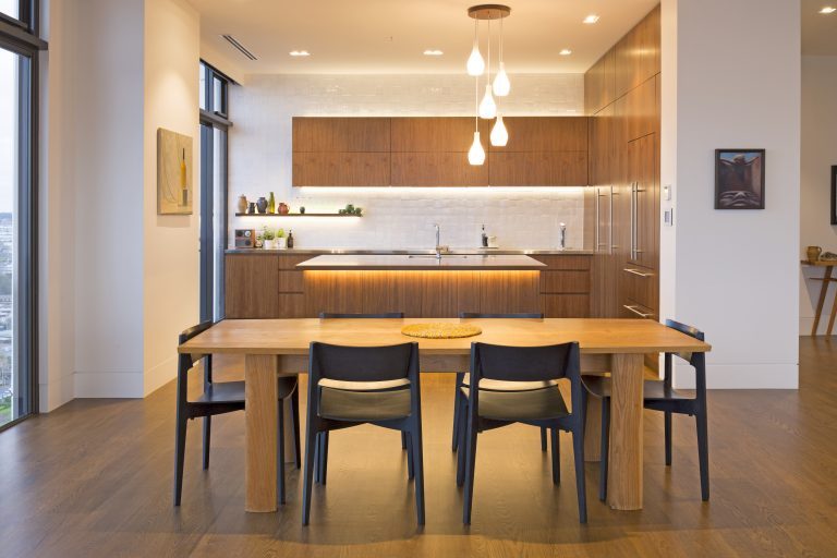 Full view of custom kitchen and dining area featuring American Walnut veneer cabinetry and dining table.