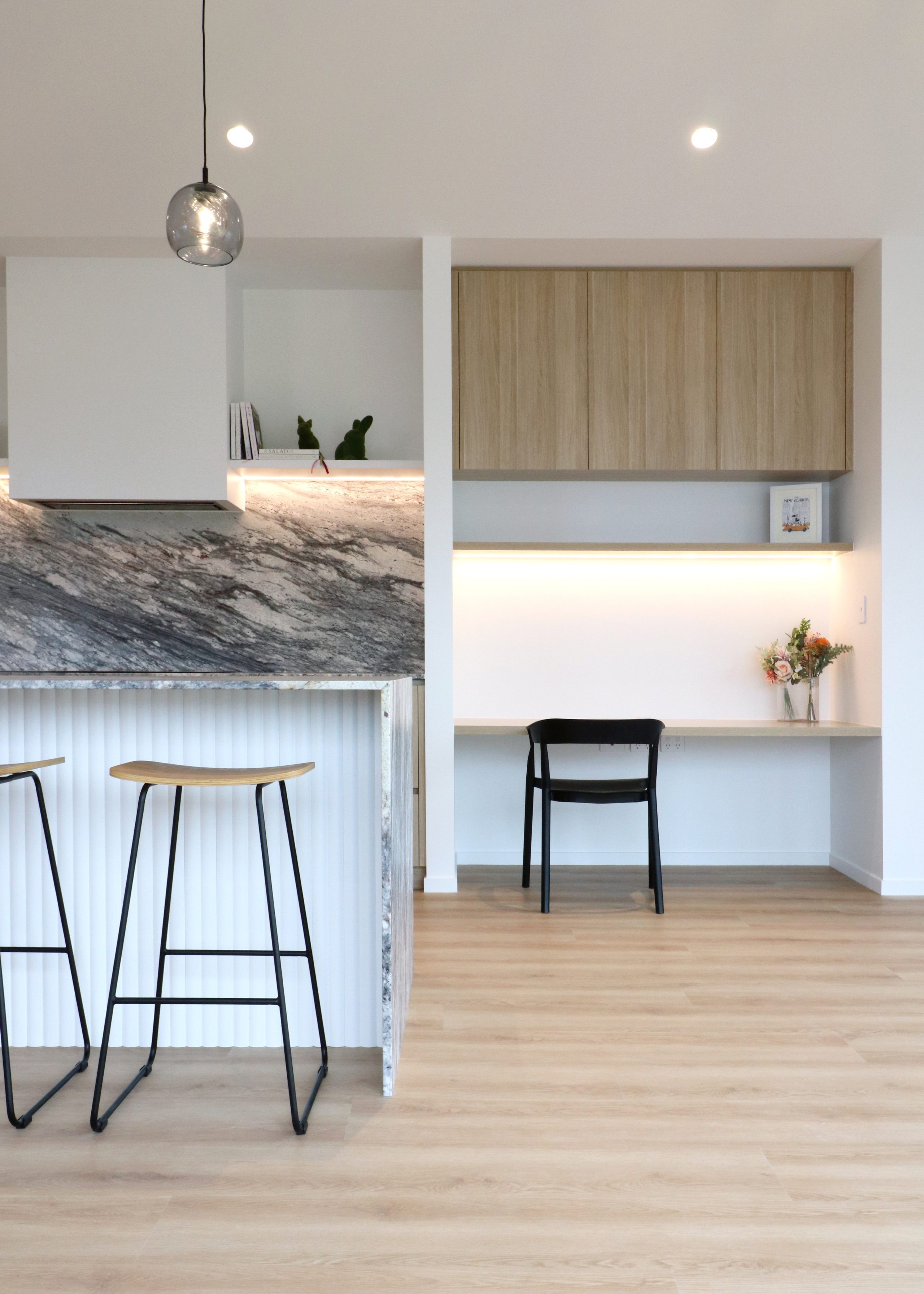 Close-up of custom study nook with Melteca Classic Oak cabinetry beside curved island waterfall end with Sensa Sant Angelo granite tops