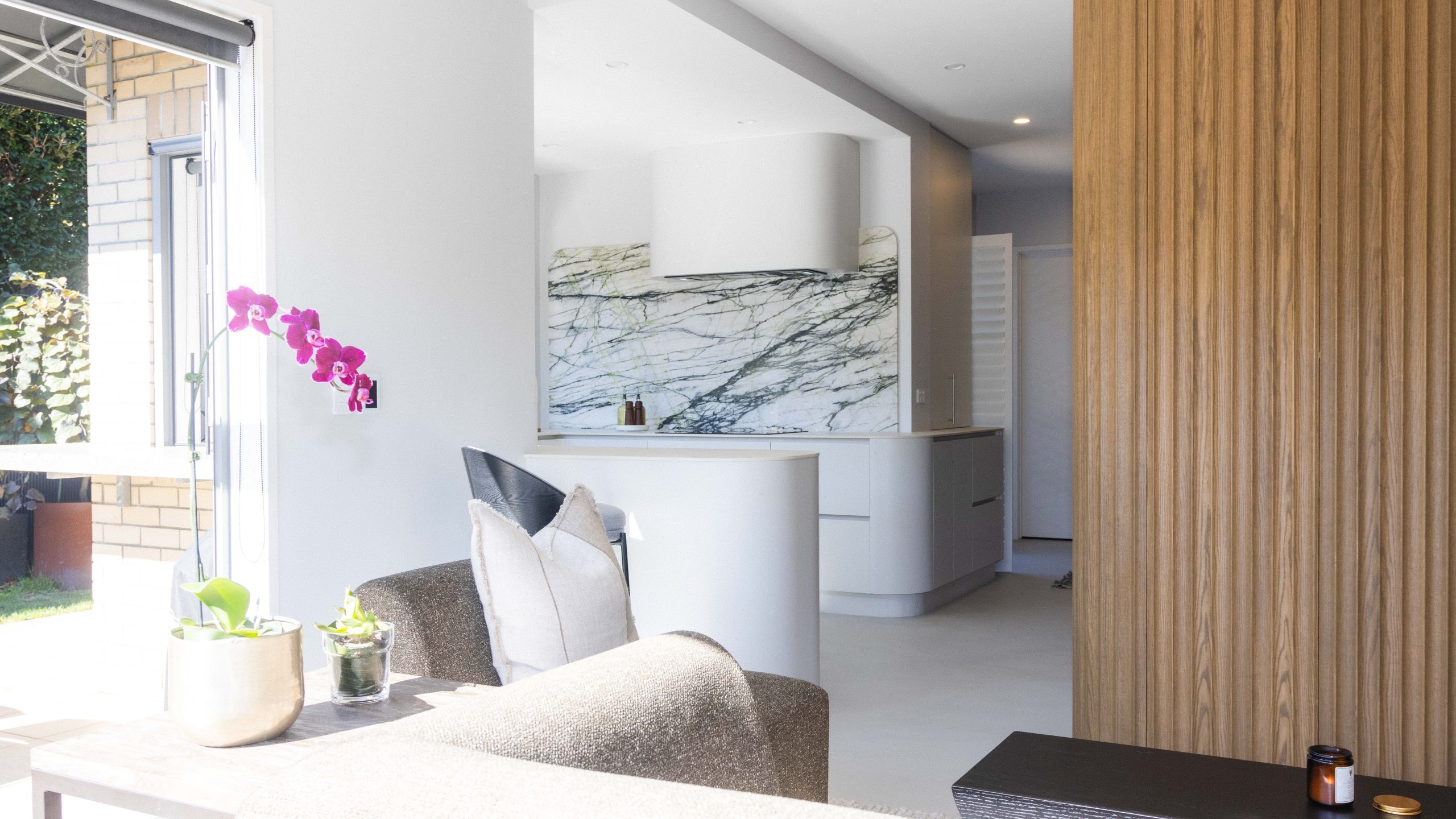Full view of custom Bayswater kitchen by Fluid Interiors featuring Ripple Flex oak tall cabinetry, Melteca Baikal and Aged Walnut units, curved marble splashback, and sculpted rangehood.