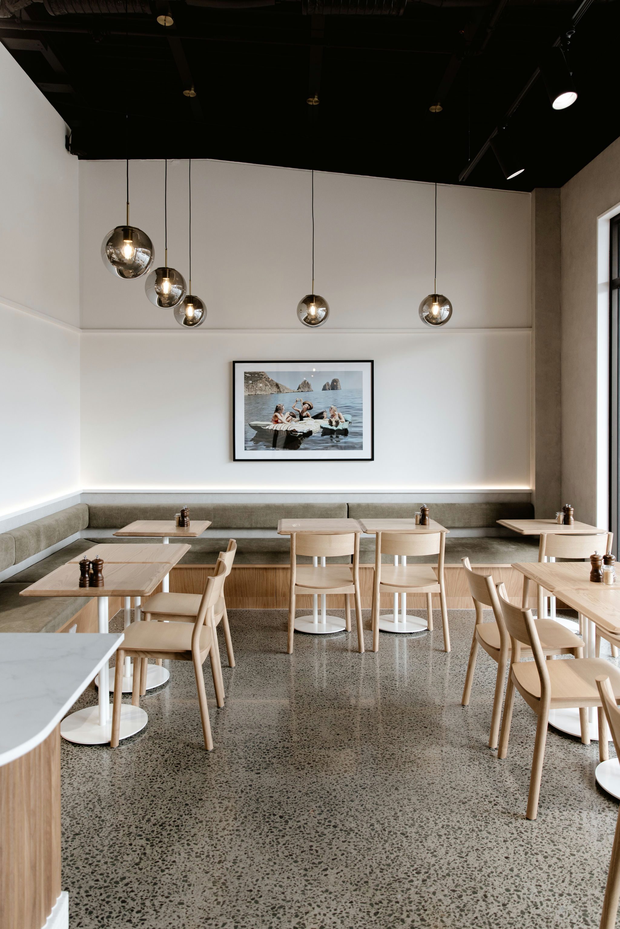 Interior seating along café walls featuring custom Oak and Walnut veneer banquet seats with hidden storage at Kinfolk Café, Long Bay