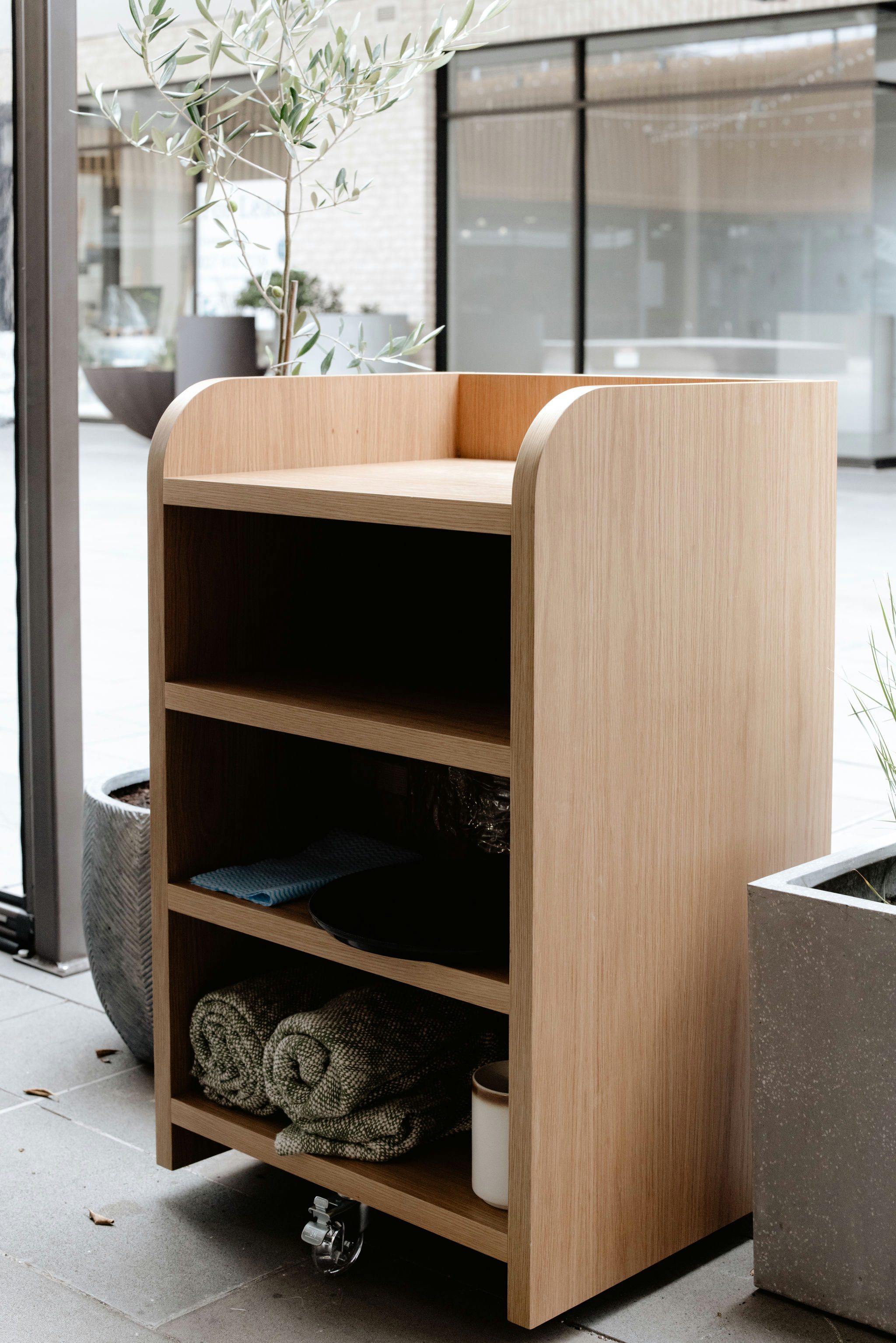 Oak storage cabinetry with curved end panels for blanket storage