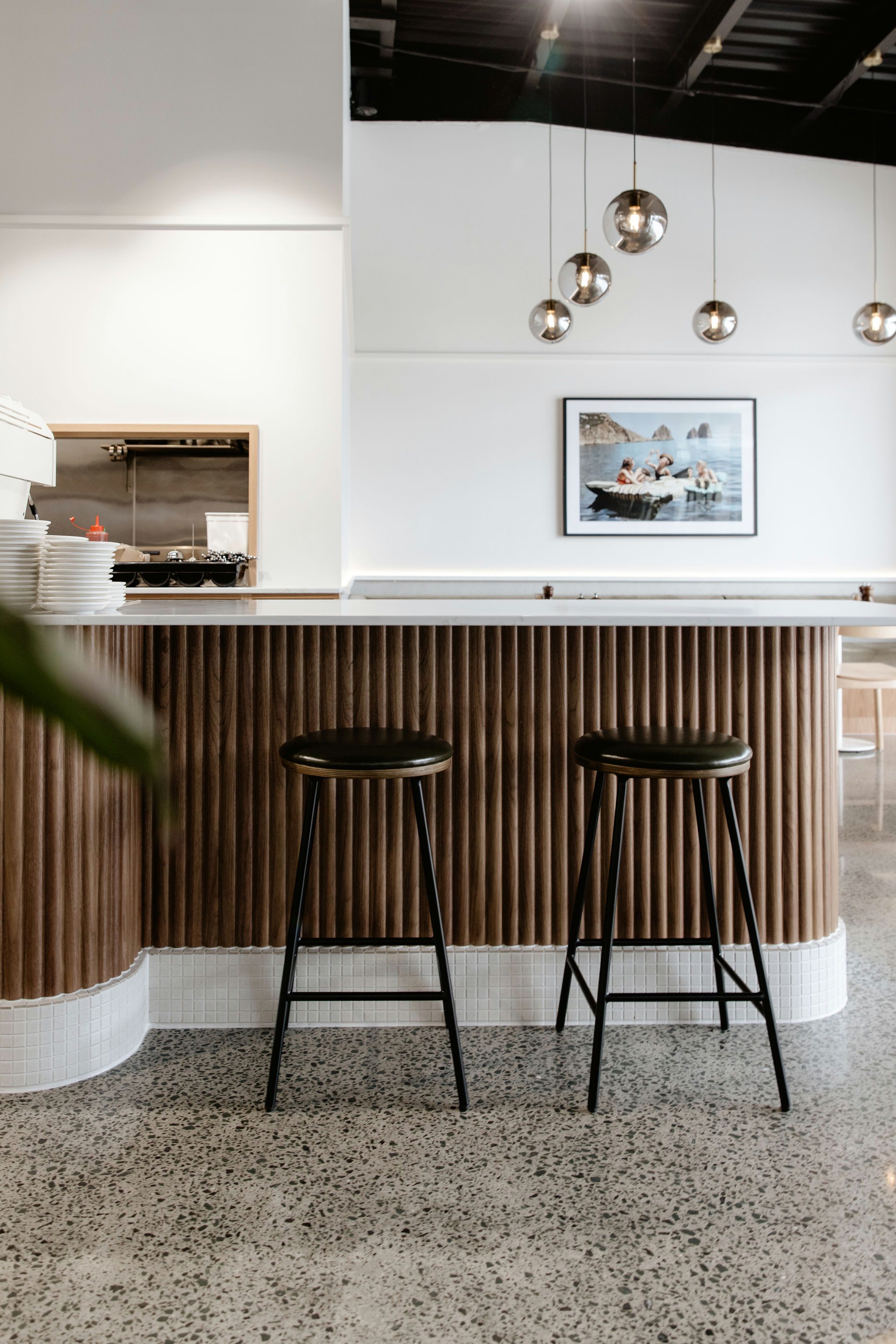 Portrait view of Kinfolk Café interior showing custom counterfront with Walnut Wave Flex panels and Prime Stone Calacatta Gold countertops, alongside Oak and Walnut veneer seating and warm natural textures