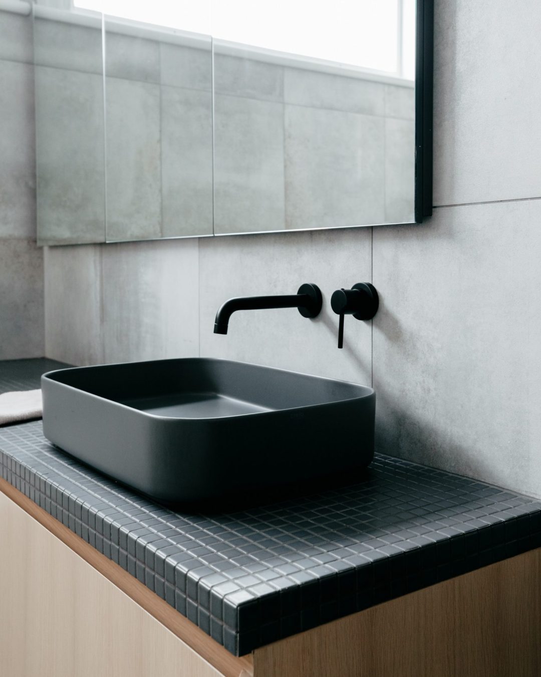 Custom handleless oak bathroom vanity with black tiled benchtop in Herne Bay home by Fluid Interiors.