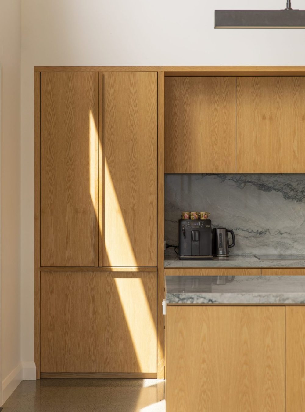 Close-up of integrated fridge with custom American oak cabinetry and bespoke handles