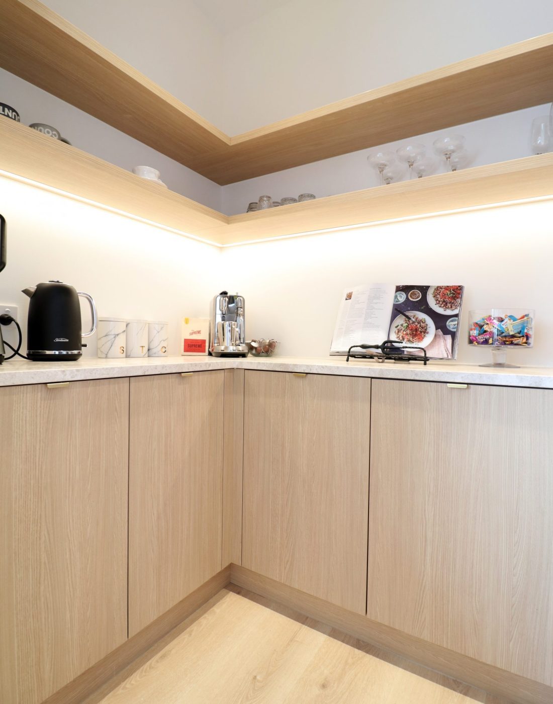 Interior scullery view in custom Wainui kitchen by Fluid Interiors, showing corner cabinetry, open shelving, and consistent aged ash Melteca Puregrain finishes.